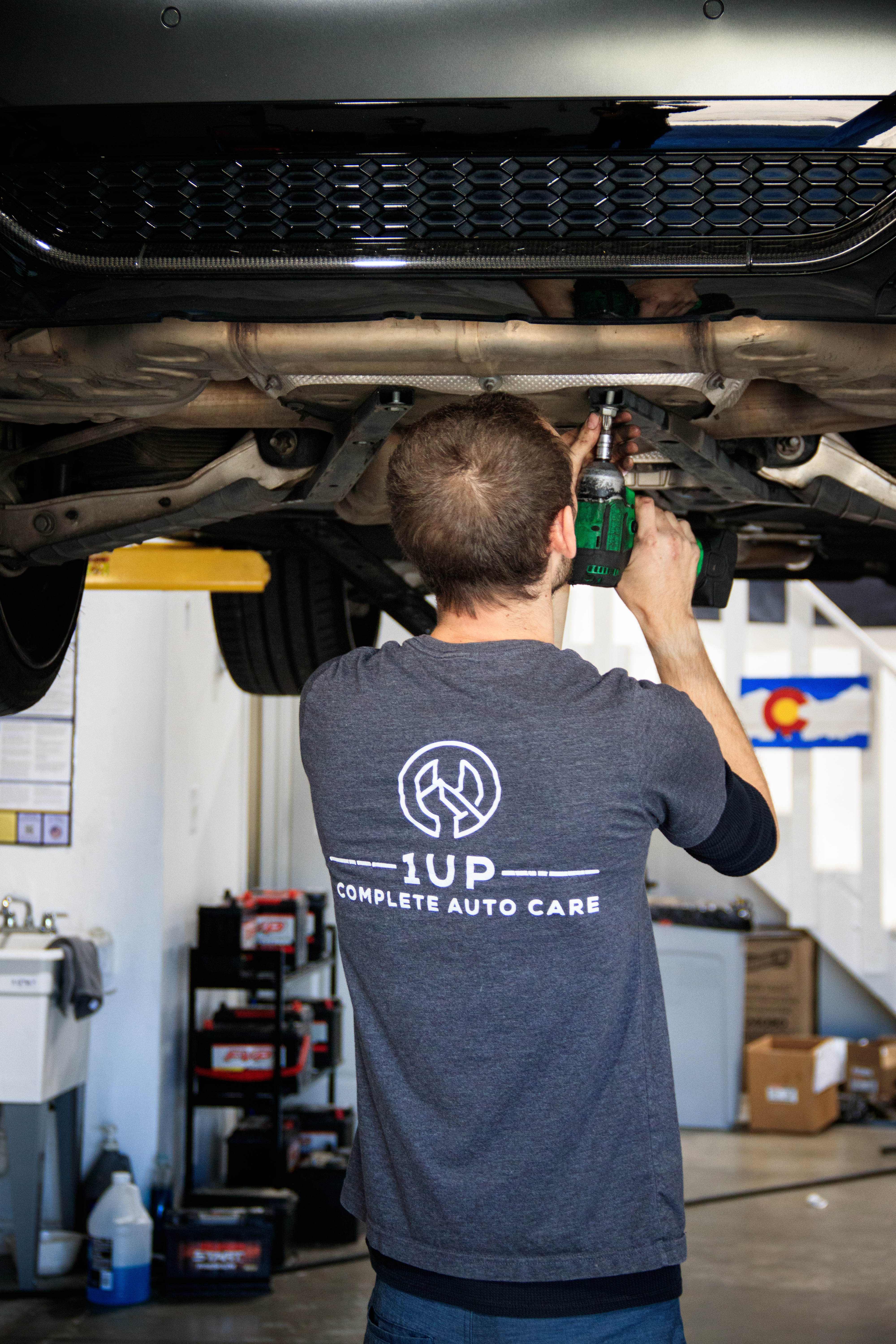 1UP mechanic performing vehicle maintenance underneath a car